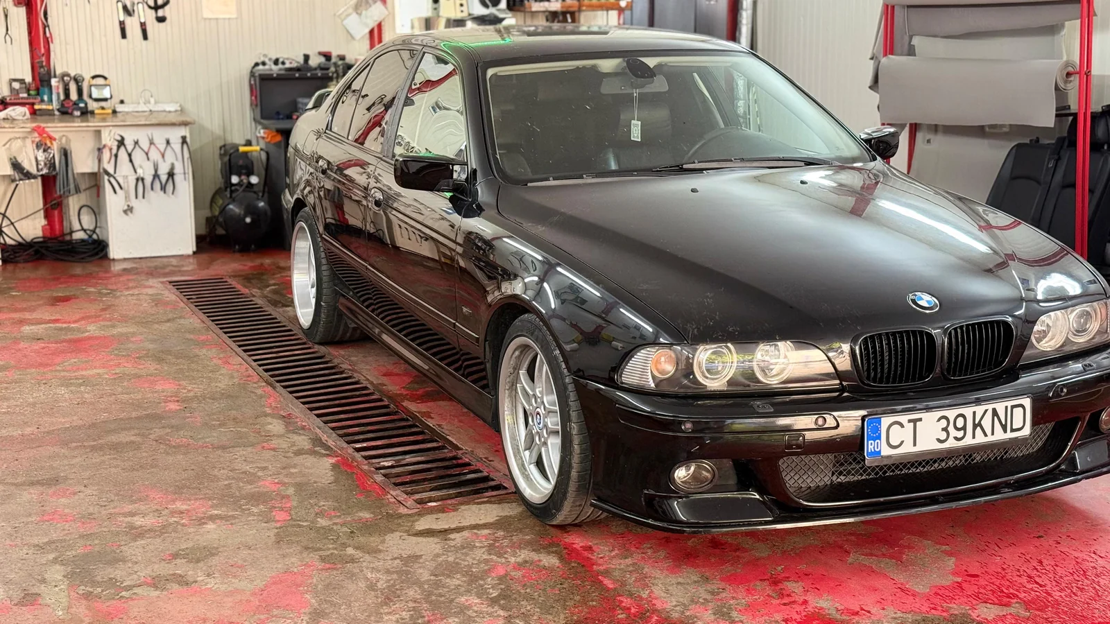 BMW negru în atelier — detaliu al caroseriei și al finisajului.